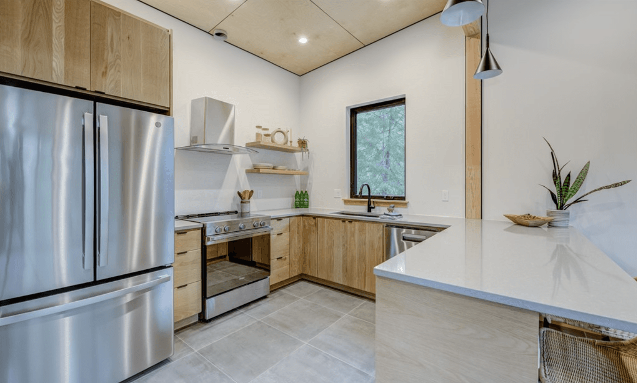 Interior view of kitchen with stainless steel appliances, white counters and modern cabinetry