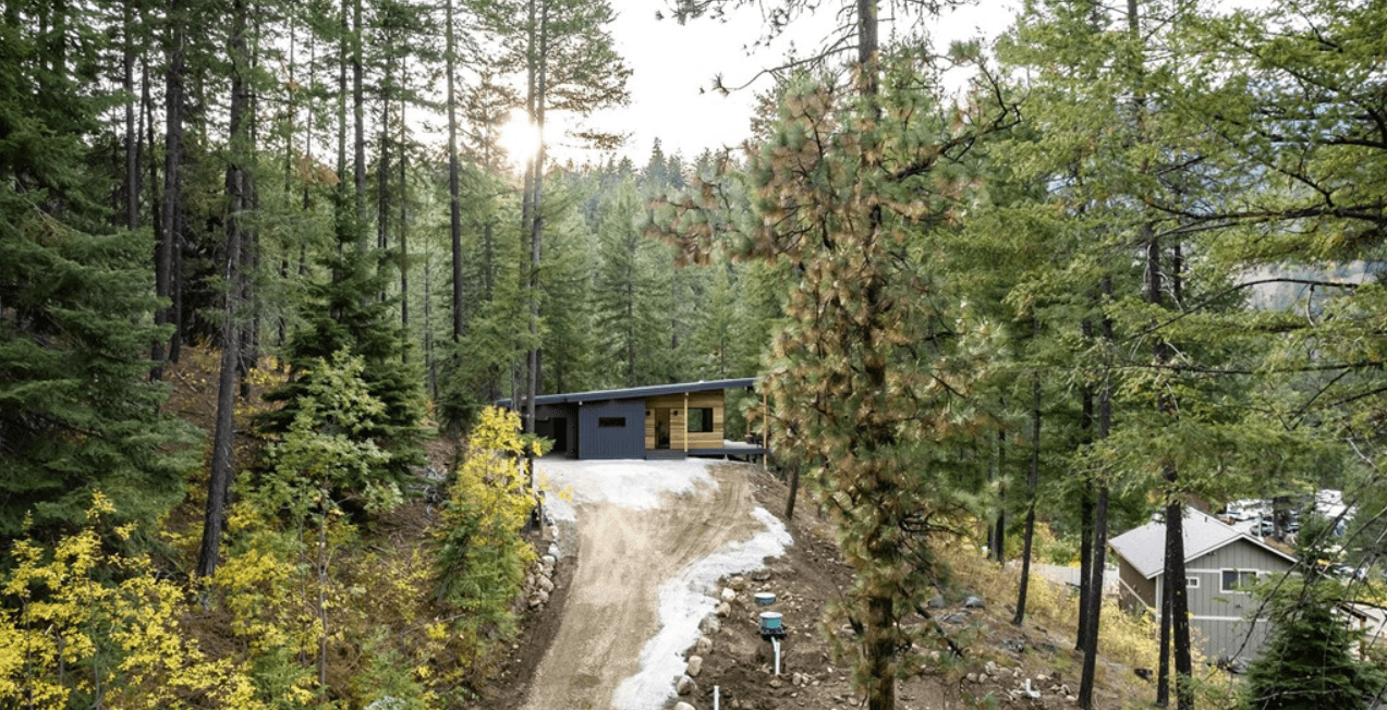 Drone view of newly constructed modern home atop a forested rise.