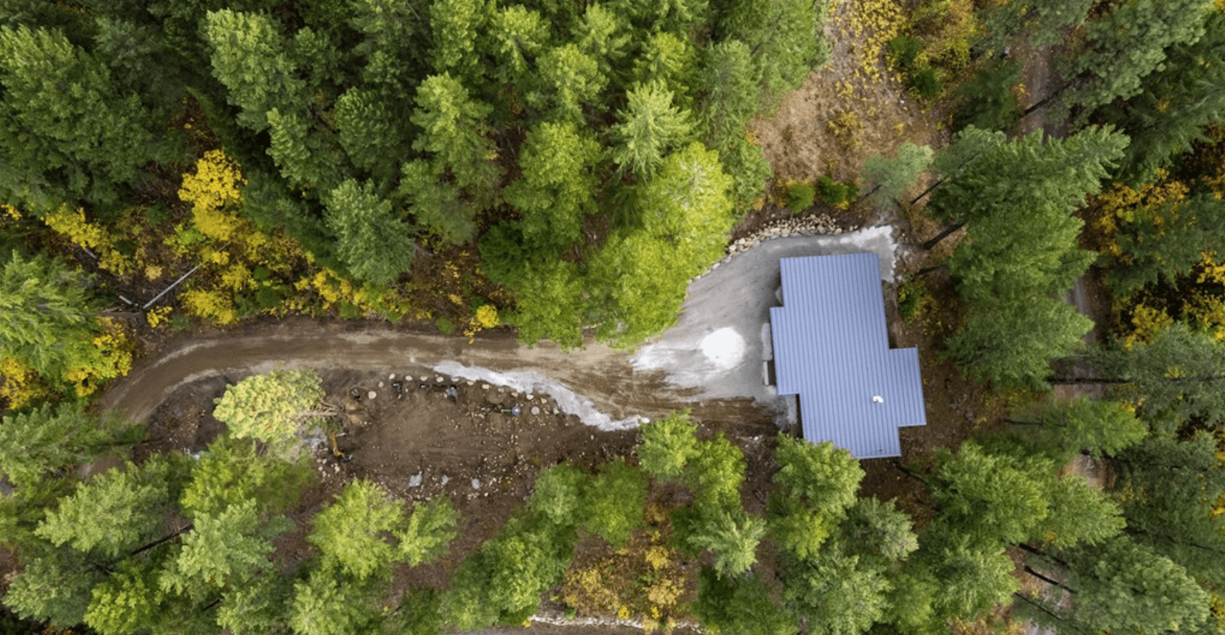 Top down view of a modern, newly constructed single story home within a forested, mountainous area