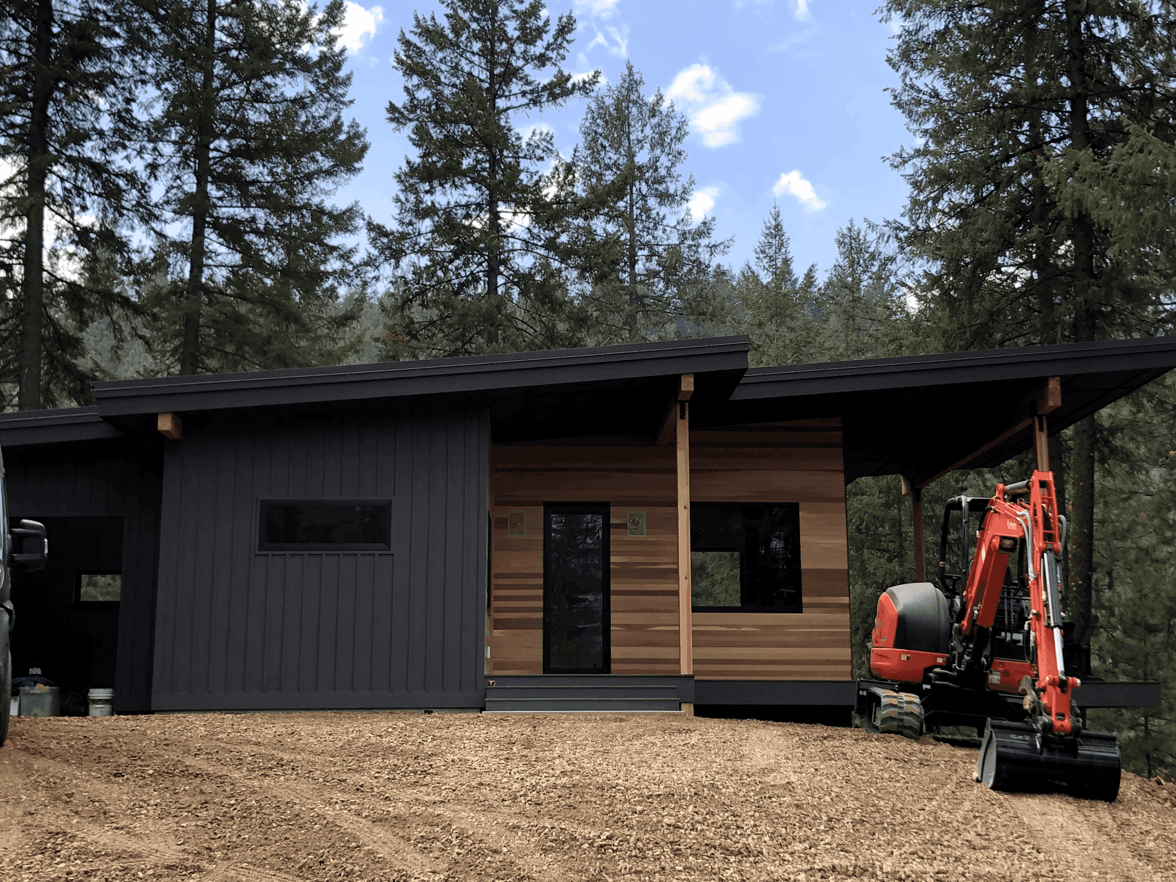 Front profile of newly constructed home with dark metal finishes and wood accents