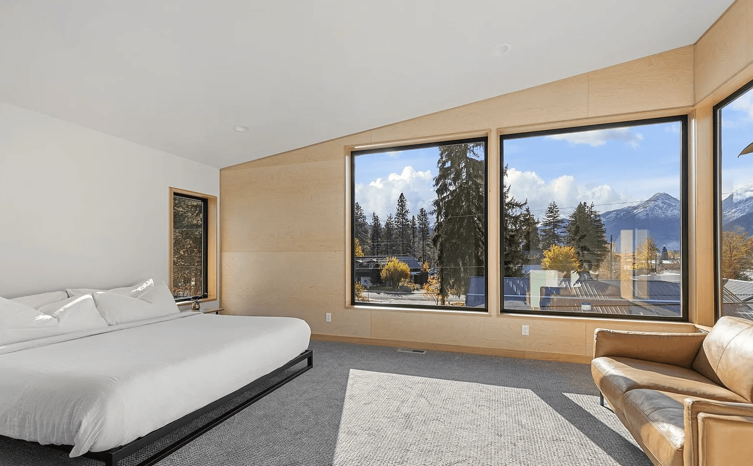 Interior of modern, newly constructed master bedroom with, bed, sofa and mountain views