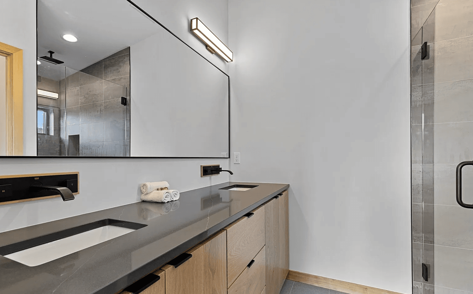 Interior of modern bathroom showing dual sinks and tiled shower