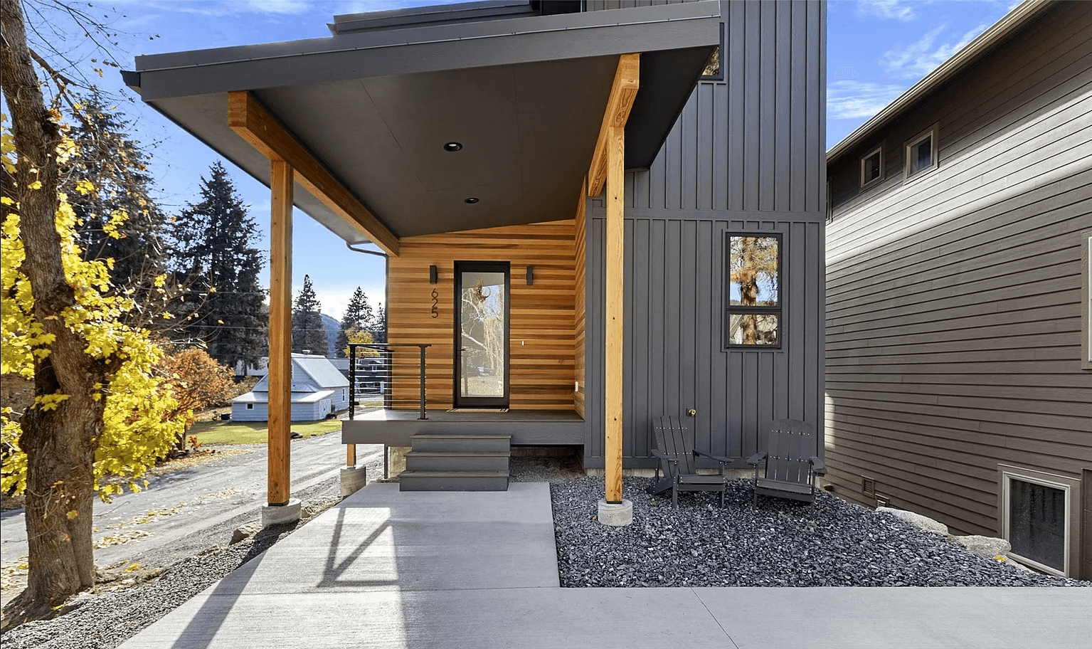 Front profile of modern three-story house with large windows and wooden accents