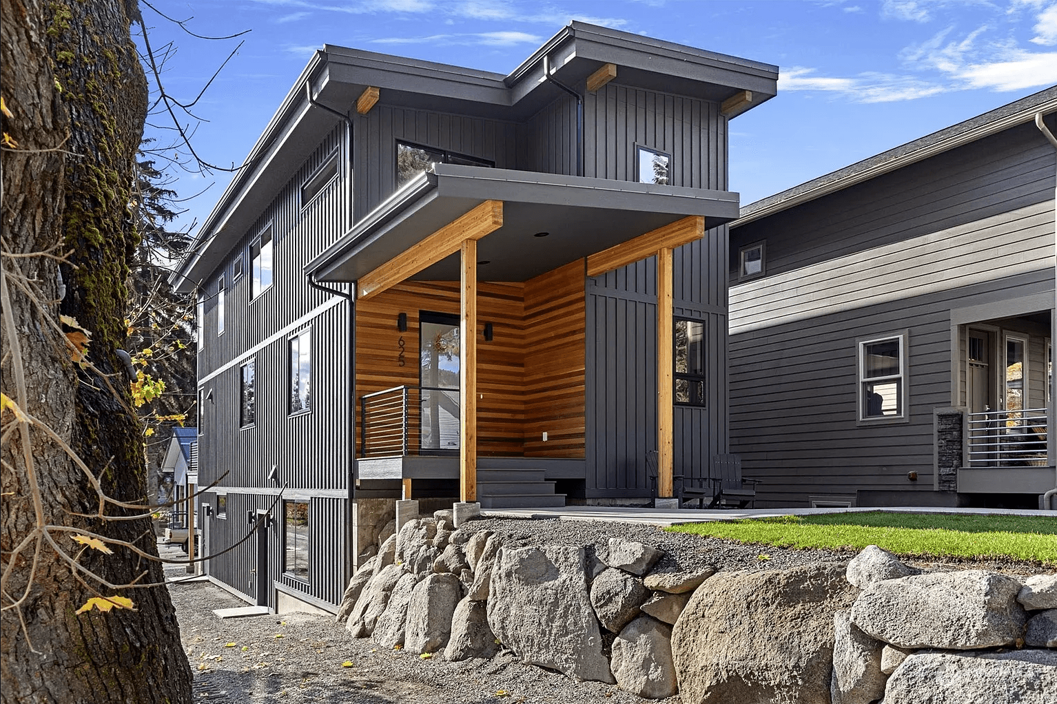 Angled front profile of modern three-story house with large windows and wooden accents