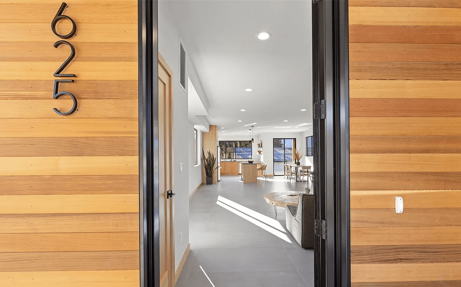 View from the perspective of an open front door into the interior of a newly constructed modern home with open living space