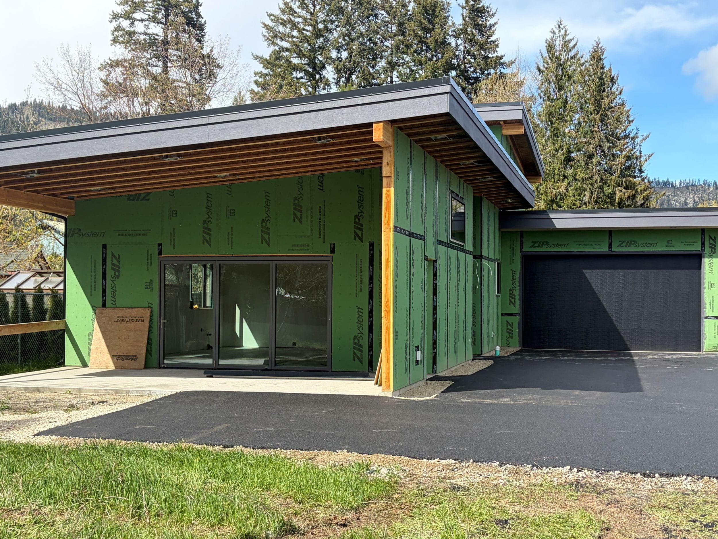 Exterior of Orchard Street house showing garage and exterior living room glass doors onto covered patio, prior to siding being applied.