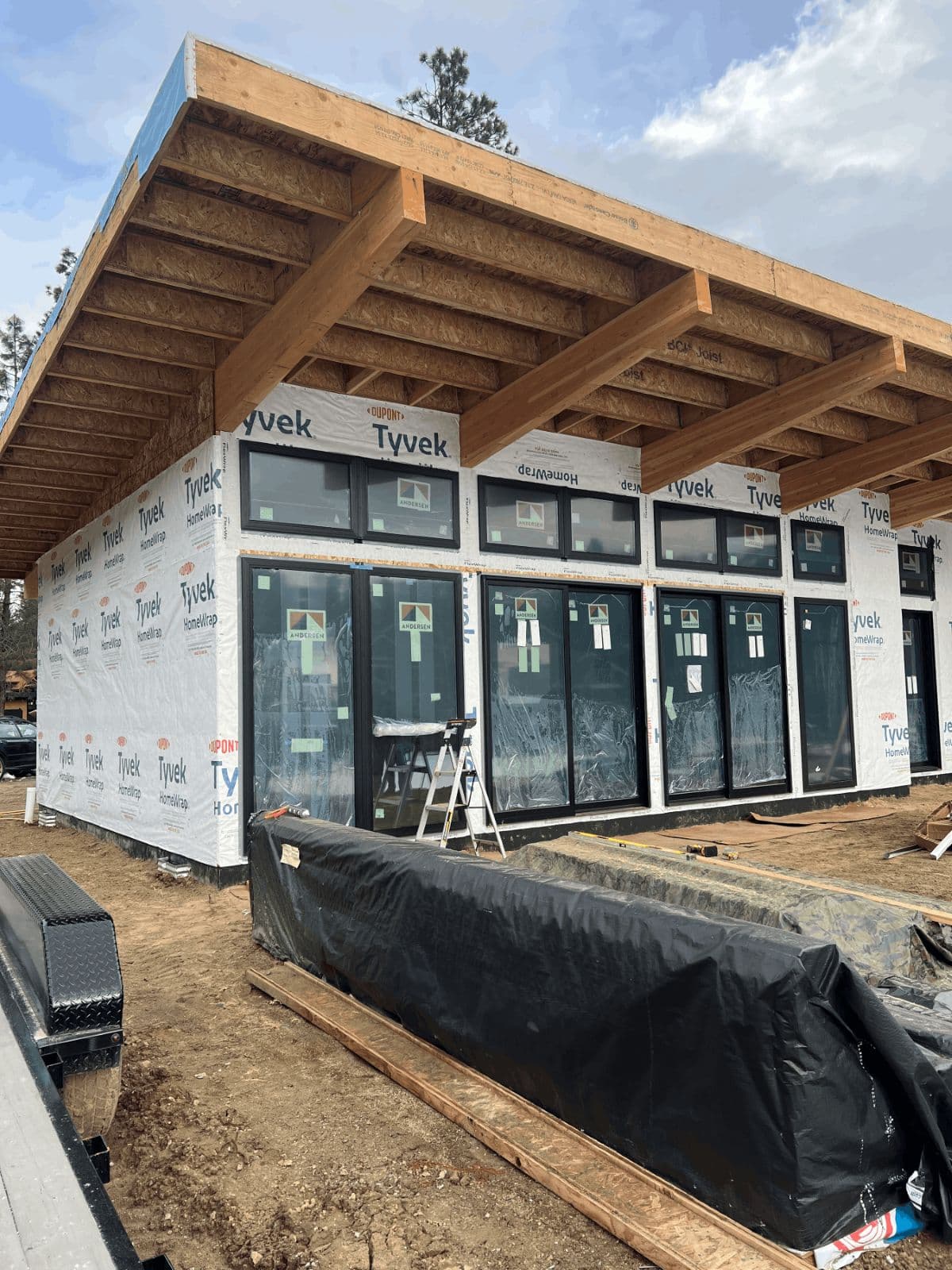 Exterior of home with large windows and wooden accents prior to siding and exterior finishes