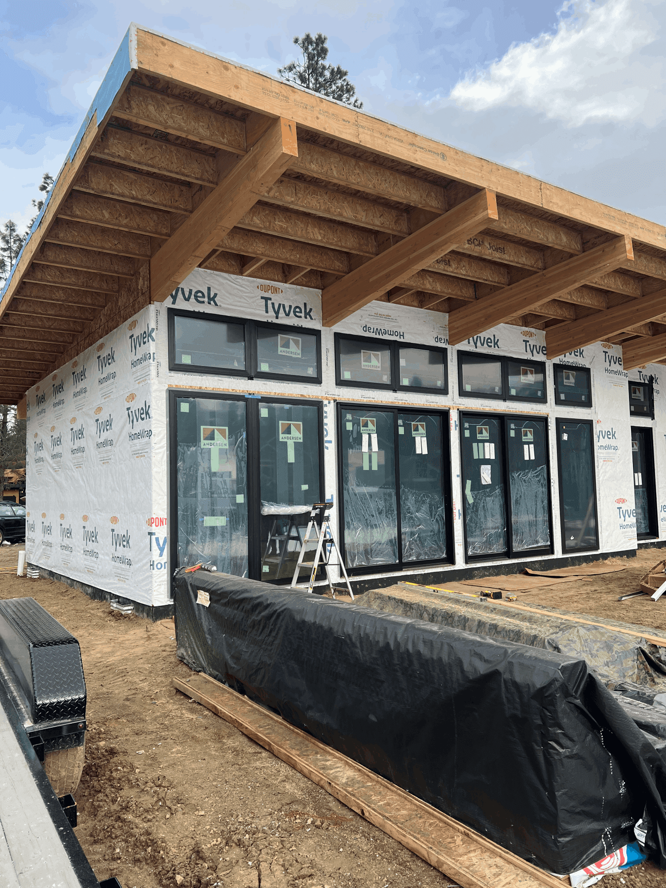 Exterior of home with large windows and wooden accents prior to siding and exterior finishes