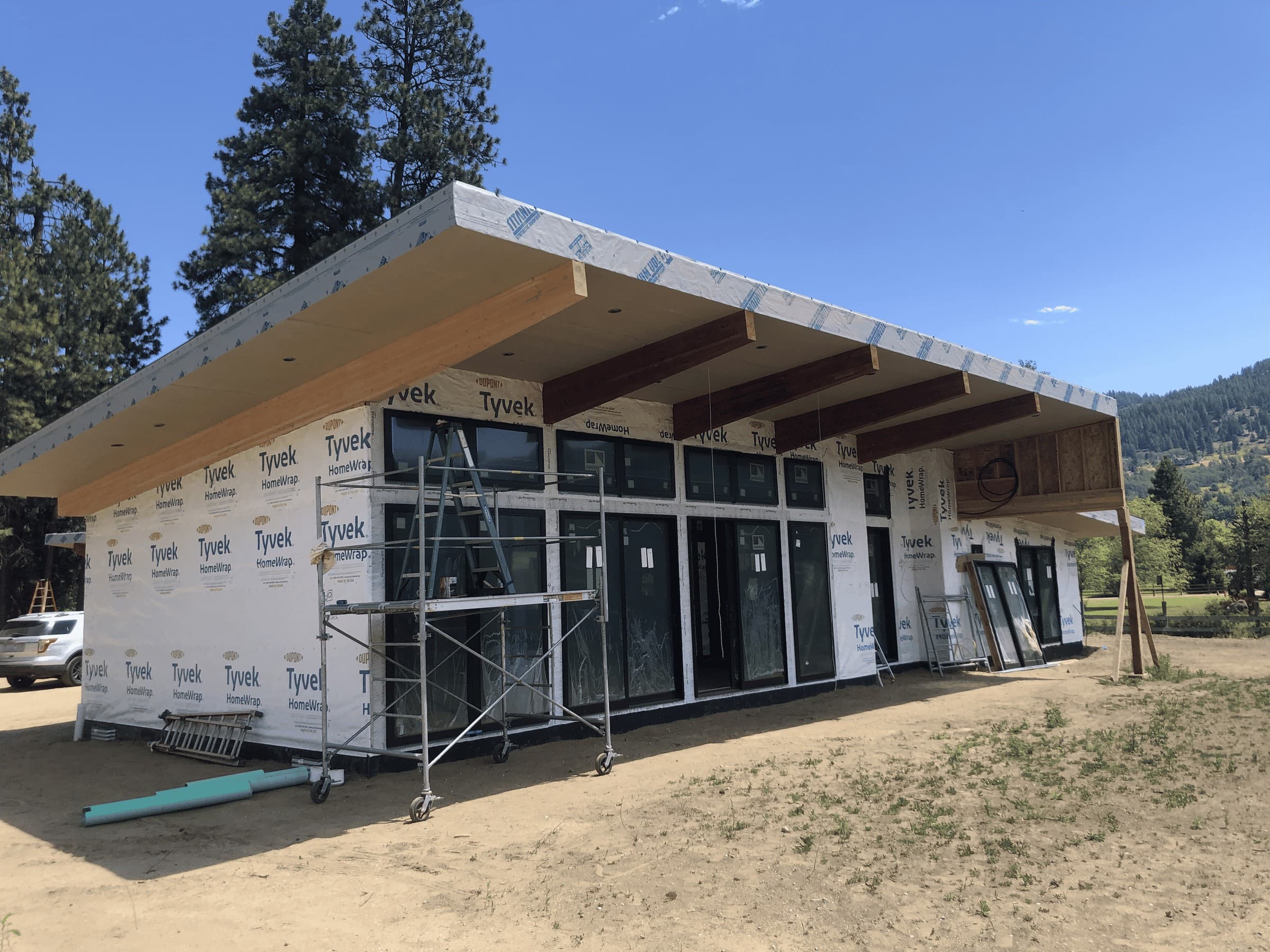 Exterior of home with large windows and wooden accents prior to siding and exterior finishes