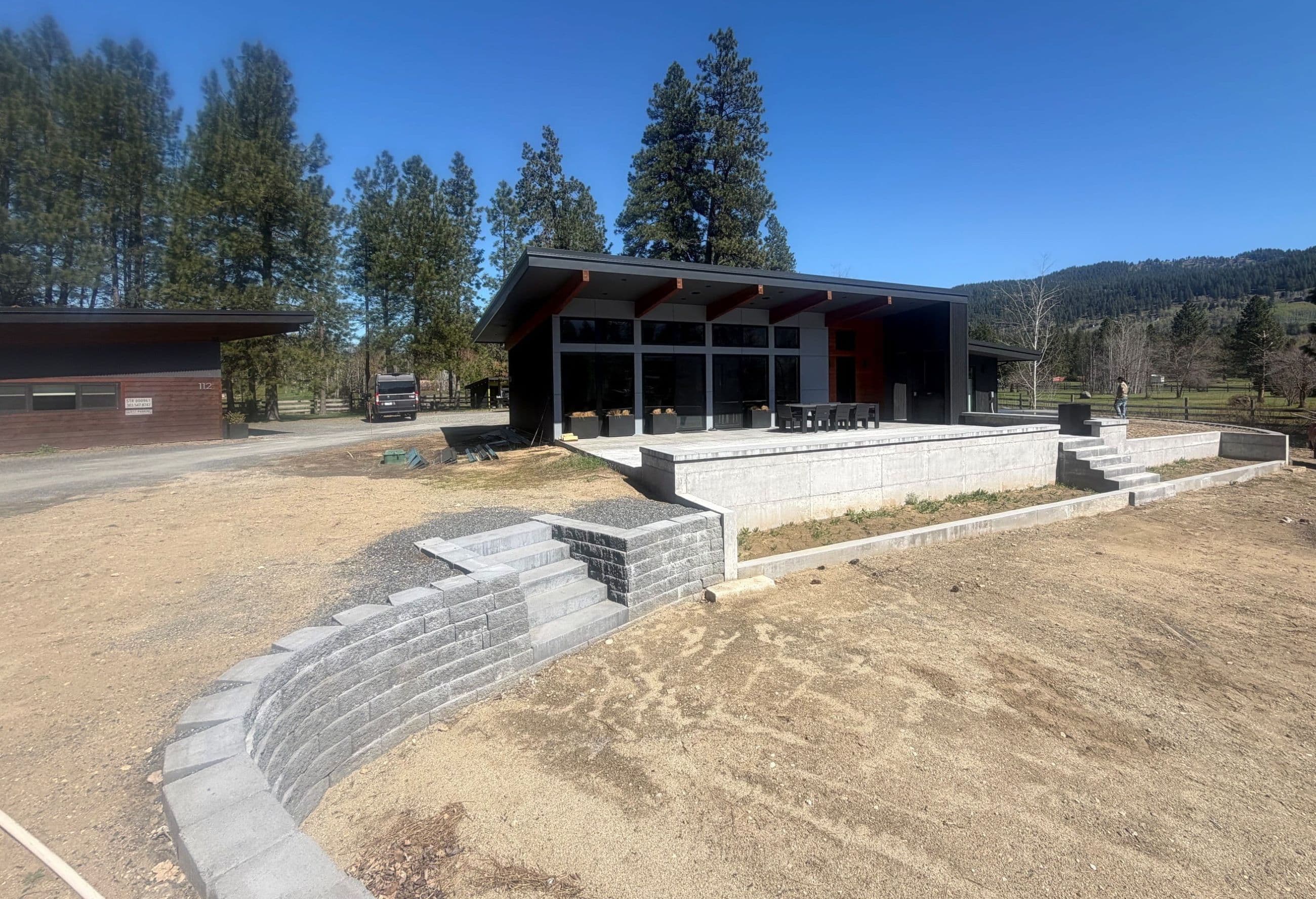 Picture of property showing custom built modern home, accessory dwelling unit and terraced terrain with concrete walls prior to landscaping