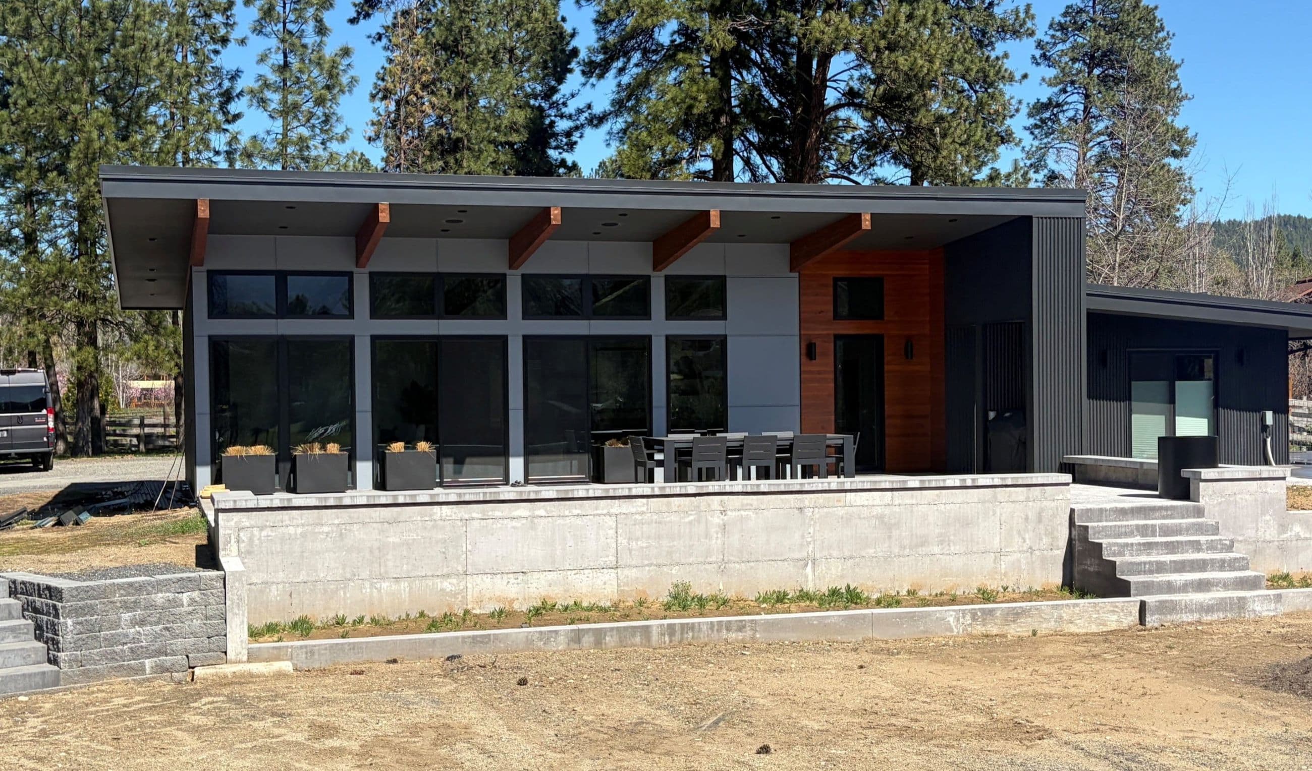 Exterior of modern one story home with expansive windows, large outdoor patio and terraced landscaping