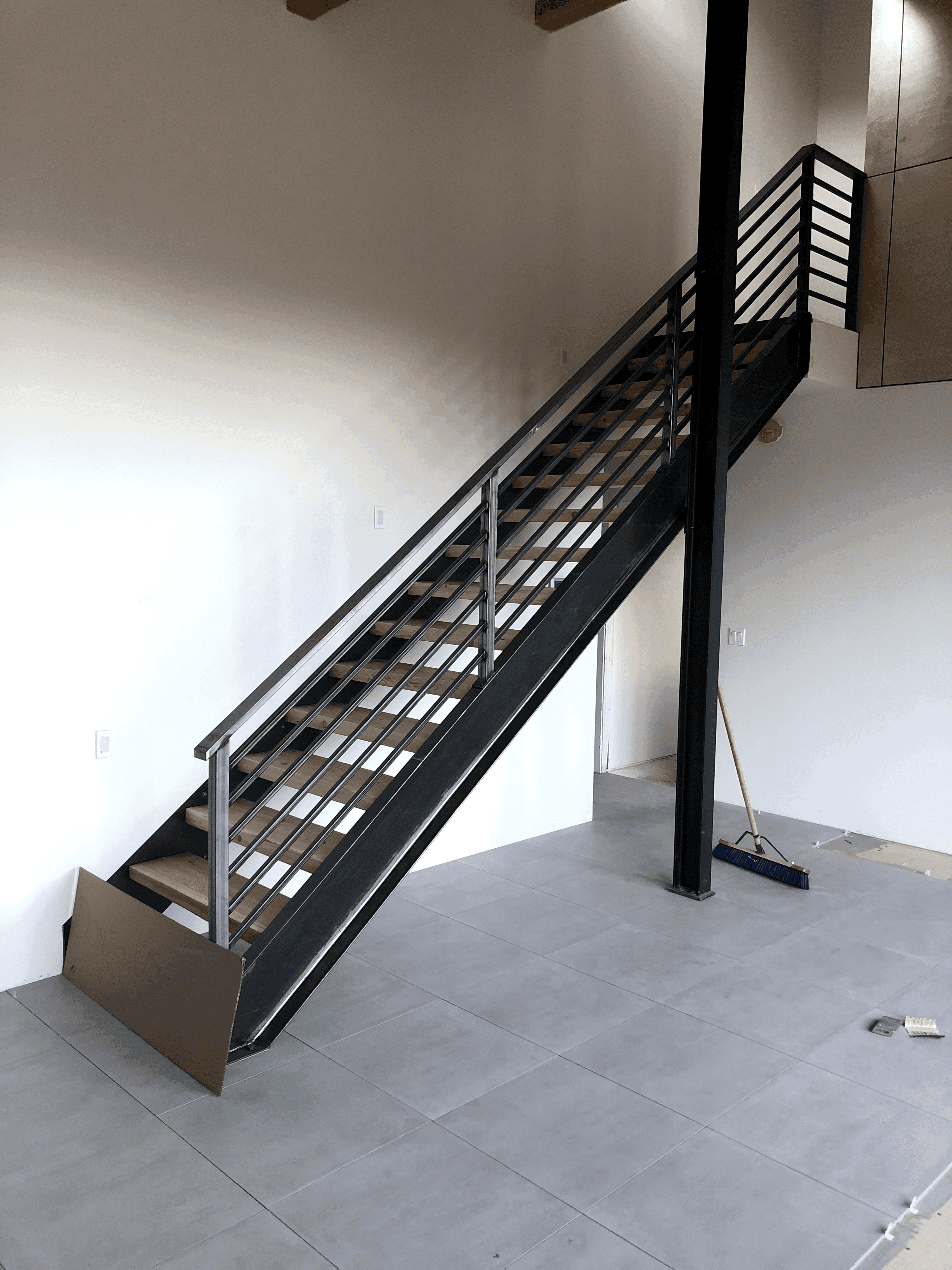 Modern interior staircase with hardwood steps and dark metal frame and railing
