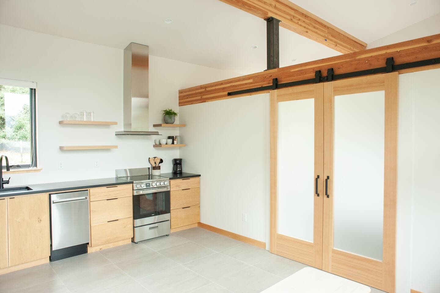 Interior of modern accessory dwelling unit showing kitchen with stainless steel appliances and sliding interior frosted glass doors