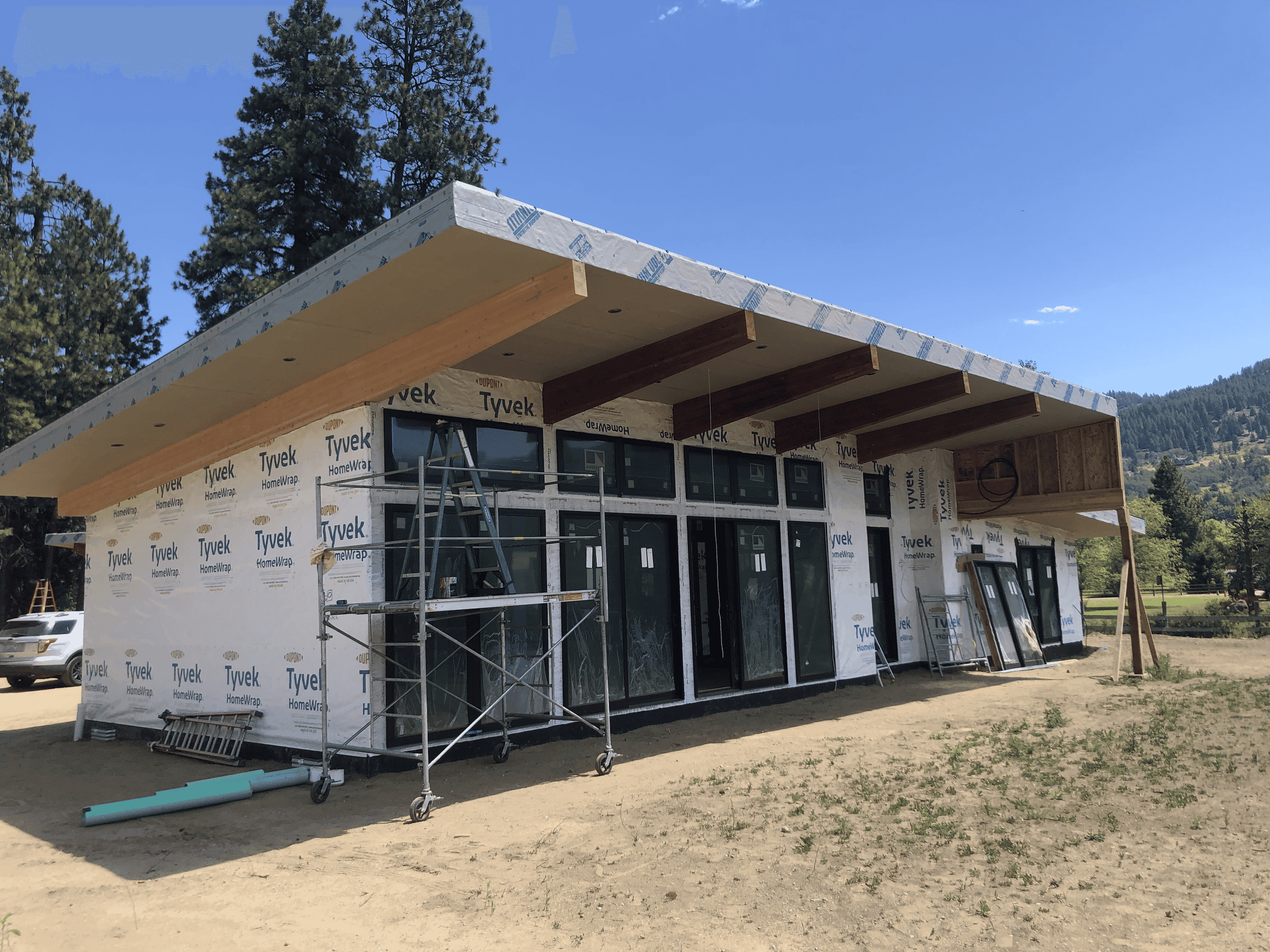 Exterior of home with large windows and wooden accents prior to siding and exterior finishes